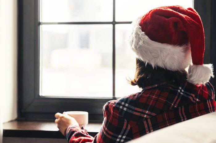Image of a woman wearing a santa hat looking out a window